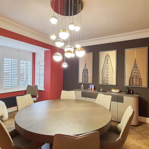 Contemporary dining room with statement lighting and warm modern decor designed by Farr Better Interiors, interior designer Hertfordshire